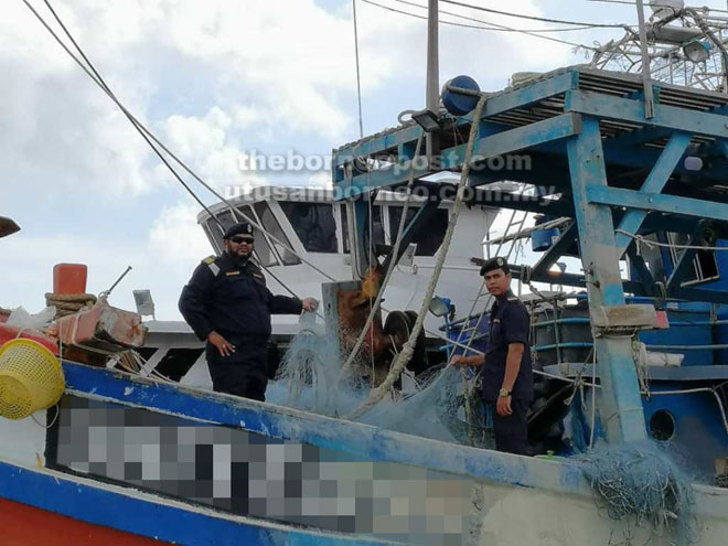 Shahref (kiri) memeriksa kapal nelayan asing yang dirampas APMM.