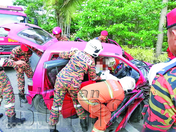 ANGGOTA bomba berusaha mengeluarkan mangsa yang terperangkap dalam kenderaan itu.