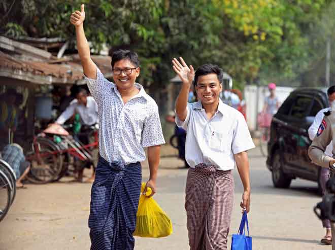  Wa Lone (kiri) dan Kyaw Soe Oo mengangkat tangan ketika berjalan keluar dari penjara Insein di Yangon, Myanmar semalam selepas menerima pengampunan presiden. — Gambar Reuters