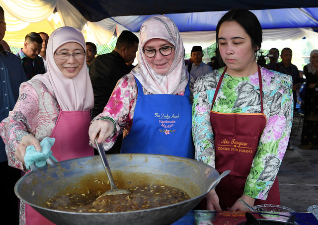 Raja Pemaisuri Agong Tunku Azizah Aminah Maimunah Iskandariah (tengah) bersama anakanda Tengku Puteri Jihan Azizah 'Athiyatullah (kanan) berkenan memasak sendiri bahan-bahan yang akan digunakan untuk membuat bubur lambuk sempena lawatan di Rumah Kanak-kanak Tengku Budriah hari ini. Turut hadir Timbalan Perdana Menteri Datuk Seri Wan Azizah Wan Ismail. - Gambar Bernama 