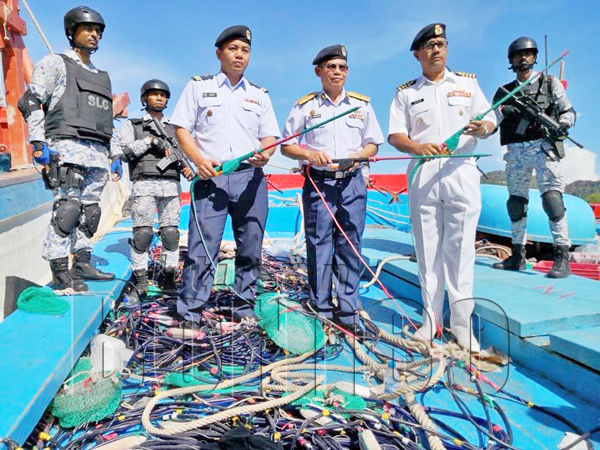 KAMARUSZAMAN (tengah) bersama Azhar (kanan) dan Pegawai Penyiasat Maritim menunjukkan peralatan elektrik yang diubahsuai untuk menangkap ikan.