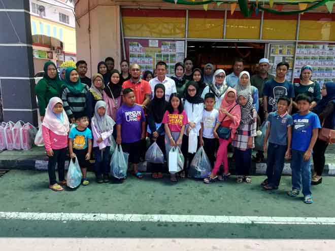  Anak-anak yatim dari kira-kira10 kampung  bersama Mazlan (lima kiri, barisan kedua) bergambar bersama selepas pergi membeli-belah di pasar raya Utama Jaya semalam. — Gambar Bernama