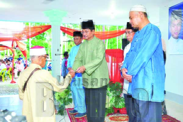 JAUJAN (dua kiri) menyampaikan bantuan kepada penerima pada Majlis Iftar Ramadan itu.