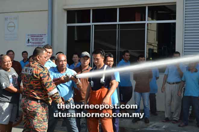  Seorang kakitangan sedang diajar oleh anggota bomba untuk mengendalikan hos air yang betul untuk memadamkan kebakaran.