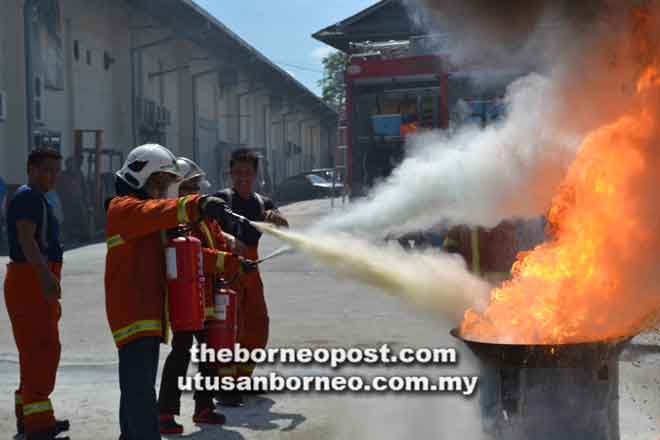  Anggota bomba menunjukkan demonstrasi penggunaan alat pemadam api yang betul untuk memadamkan api.