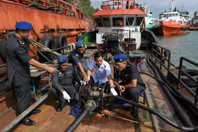  Saharuddin (dua kanan) bersama anggotanya memeriksa kapal yang membawa 104,200 liter minyak diesel secara haram di Jeti Sungai Kuang dekat Kemaman, semalam. — Gambar Bernama