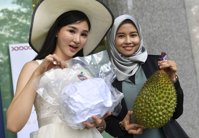  Nur Alifah Najwa Ramli dari Beho Fresh Sdn Bhd bersama He. Yuhan dari Yechen iaitu syarikat pengimport durian China menunjukkan durian sejuk beku semasa majlis pelancaran pengeksportan sulung buah durian sejuk beku dalam bentuk biji dari Malaysia ke China di Kementerian Pertanian dan Industri Asas Tani semalam. — Gambar Bernama