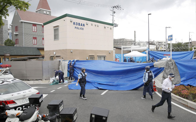  Para pegawai polis menjalankan siasatan di tempat kejadian di hadapan balai polis di Suita, wilayah barat Osaka kelmarin dalam gambar serahan Kyodo. — Gambar Reuters