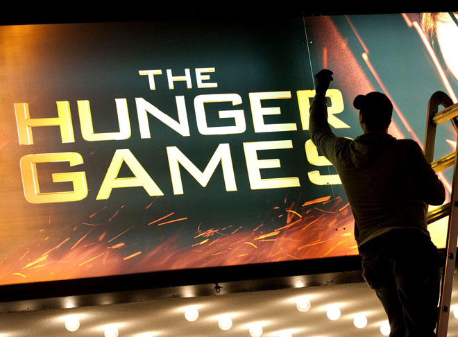  Gambar fail yang diambil pada 22 Mac 2012 ini menunjukkan seorang pekerja membersihkan papan iklan ‘The Hunger Games di Ziegfeld Theatre, New York. — Gambar AFP