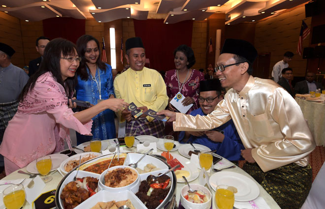  Kok (kiri) menyampaikan sumbangan duit raya kepada warga Kementerian Industri Utama pada Majlis Ramah Mesra dan Sambutan Hari Raya Aidilfitri semalam. — Gambar Bernama