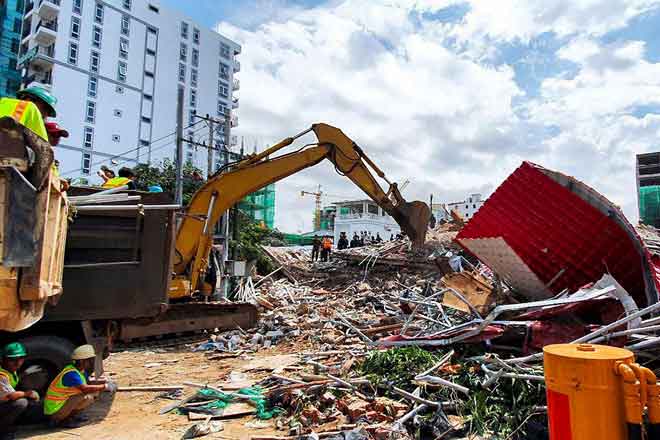  Penyelamat menggunakan jentolak untuk membersih puing selepas bangunan yang sedang dibina di Sihanoukville runtuh, semalam. — Gambar AFP