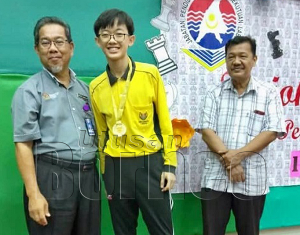 MOHD Jamatin (kiri) menyampaikan medal kepada juara Lelaki 18, Wong Wei Hao dari SMK Labuan. Turut kelihatan Subari Dwar (kanan).