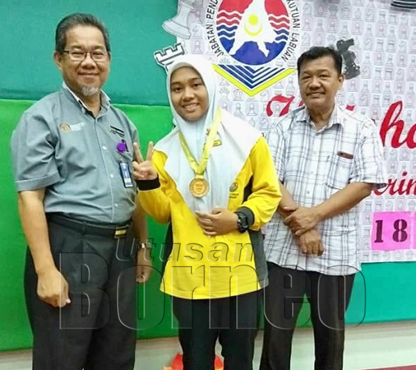 PEMAIN SMK Labuan, Nornadiah Jeinia menerima medal juara Kategori P18 daripada Mohd Jamatin sambil diperhatikan Subari Dwar.