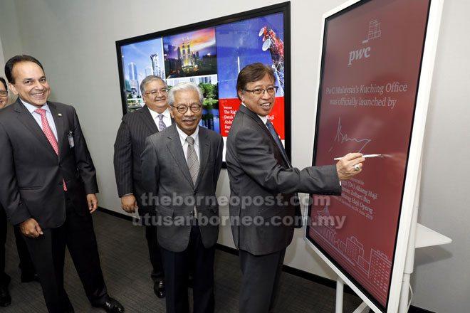  Abang Johari menurunkan tandatangan di atas plak khas bagi merasmikan pejabat PwC di Kuching. Turut kelihatan (dari kiri) Sridharan, Masing dan Mohammad Faiz (belakang). — Gambar Chimon Upon