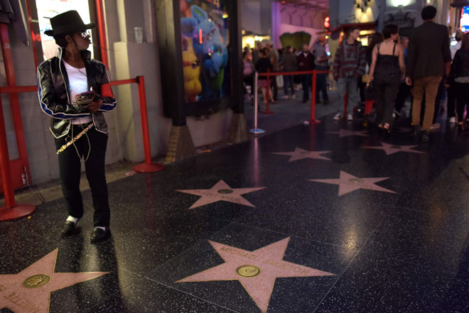  Seorang wanita berpakaian seperti Michael Jackson berdiri tidak jauh dari bintang  Hollywood Walk of Fame penyanyi itu di Hollywood pada 23 Jun lepas. — Gambar AFP