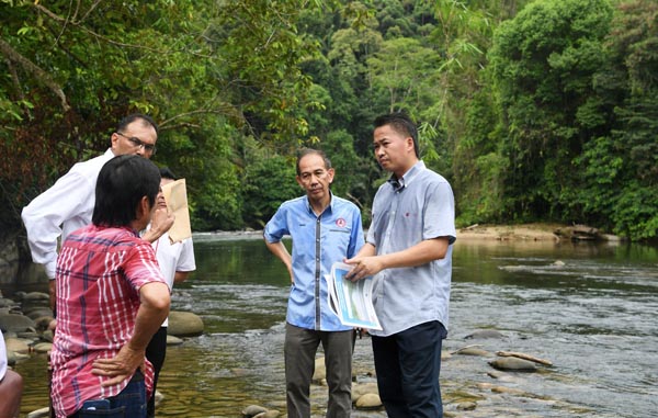 PETER (kanan) berbincang bersama penduduk sambil melihat peta lokasi Sungai Papar ketika melawat lokasi pembinaan empangan Papar.