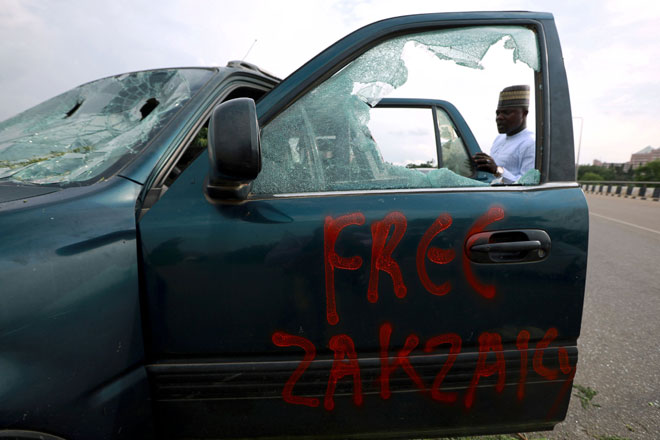  Contengan ‘Bebas Zakzaky’ dilihat pada pintu sebuah kereta yang rosak selepas pertempuran meletus antara penyokong ulama Syiah itu dan pasukan keselamatan di luar Dewan Negara di Abuja, Nigeria kelmarin. — Gambar Reuters