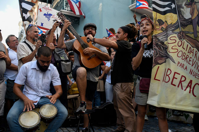  Anggota kumpulan teater Papel Machete membuat persembahan semasa menyertai bantahan untuk menuntut peletakan jawatan Rossello (kanan) di hadapan La Fortaleza di San Juan, Puerto Rico kelmarin. — Gambar Reuters