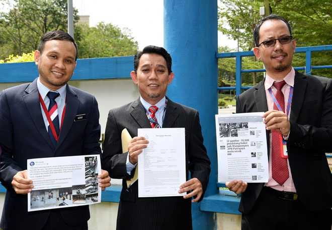  Jasri (tengah) menunjukkan laporan polis yang dibuat di Ibu Pejabat Polis Daerah Putrajaya berhubung penularan gambar di media sosial yang mendakwa ibu pejabat jabatan itu di sini diserbu pendatang asing untuk mendapatkan status kewarganegaraan. — Gambar Bernama