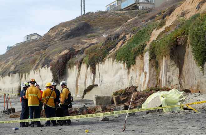  Beberapa anggota kecemasan meninjau runtuhan cerun di sebuah pantai di Encinitas, California, AS kelmarin. — Gambar Reuters