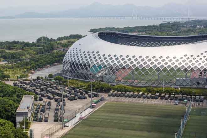  Puluhan trak dan kenderaan pengangkut anggota berperisai dilihat diparkir di luar stadium ketika ribuan tentera China berhimpun di bandar raya Shenzhen di seberang sempadan dengan Hong Kong semalam. — Gambar Reuters