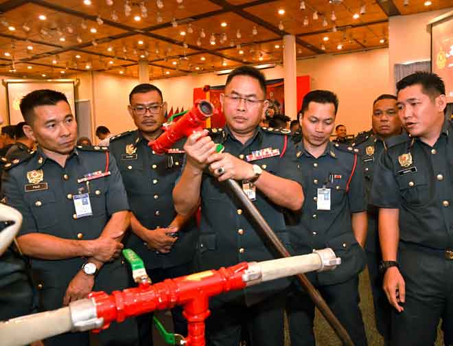  Khirudin (tengah) melihat dari dekat ‘Smart Injector ll’ yang memenangi tempat kedua pertandingan KIK Jabatan Bomba dan Penyelamat Malaysia (JBPM) Sarawak semalam. — Gambar Bernama
