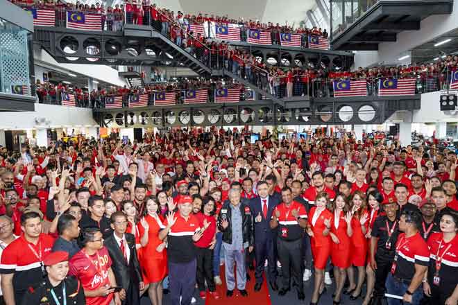  Dr Mahathir (tengah) disempulang Loke begambar ungkup kenang enggau staf AirAsia maya program nya.