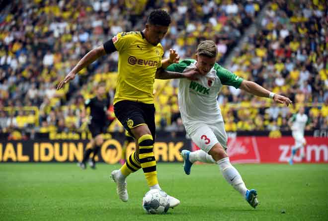  Sancho (kiri) mengawal bola ketika bersaing dengan pemain Augsburg pada perlawanan Bundesliga Jerman di Signal Iduna Park, Dortmund kelmarin. — Gambar AFP