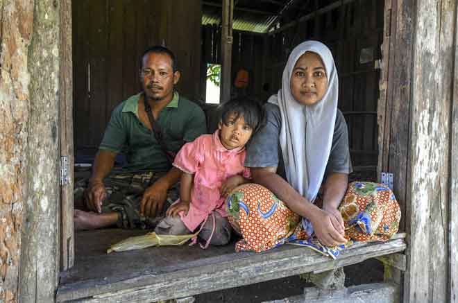   Pasangan suami isteri Mohd Zuhaidi (kiri) dan Siti Hamidah bersama anak bongsunya, Nor Syafiya (tengah) tinggal di rumah usang yang disewa mereka di Kampung Tengah dekat Kuala Krai, semalam. — Gambar Bernama