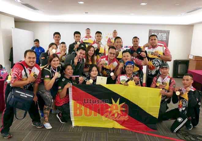  Barisan ‘puller’ Sarawak bersama Matthew dan Louise (tengah) meraikan kejayaan setelah mencapai keputusan terbaik pada kejohanan gusti lengan kebangsaan, Sabtu lalu.