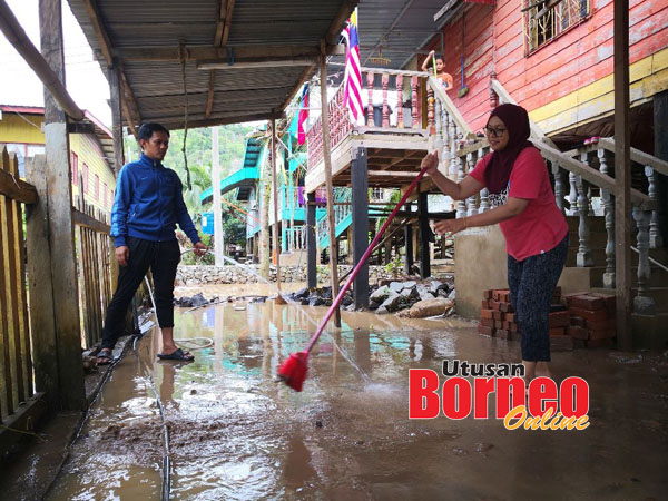  Hasman dan isterinya bergotong-royong membersihkan kawasan halaman rumah mereka akibat kesan banjir.