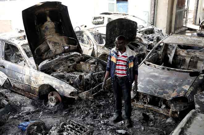  Gambar fail 5 September lalu menunjukkan usahawan Nigeria Basil Onibo, salah seorang mangsa serangan xenofobia, hanya mampu melihat kereta-kereta yang hangus di ruang pameran kedai keretanya di Johannesburg. — Gambar Reuters