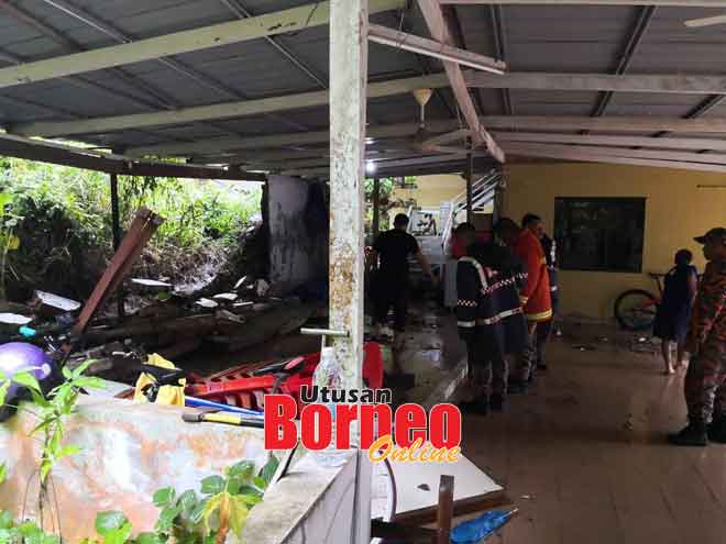  Anggota bomba membantu membersih rumah penduduk yang ditimbus tanah susur di Kampung Pemukat, petang semalam.