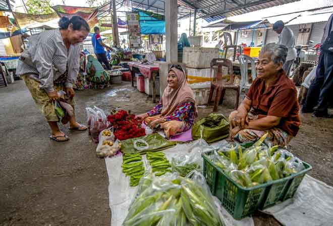  Peniaga sayur-sayuran Mek Kwan,70, (kanan) keturunan Siam Kelantan berkongsi ruang niaga bersebelahan dengan peniaga Melayu, Che Sopiah Awang, 70, (tengah)  di Pasar Bunohan di Tumpat, semalam. — Gambar Bernama