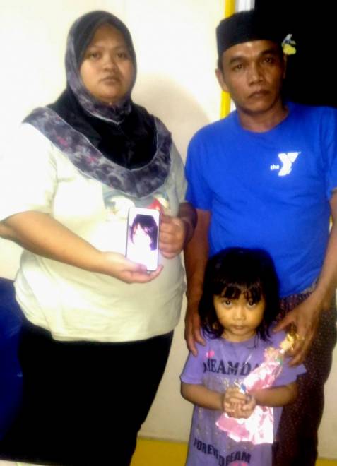  Anisah (kiri) bersama suaminya dan anak kedua mereka menunjukkan gambar Puteri Nurardiana yang masih belum ditemui pada telefon bimbit.