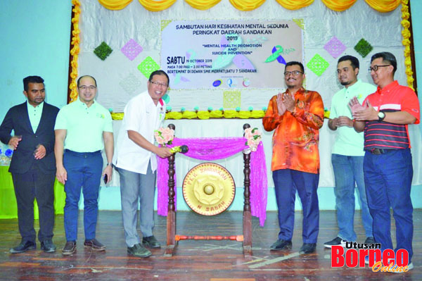  Teo (tiga, kiri) memalu gong sebagai simbolik merasmikan Sambutan Hari Kesihatan Mental Sedunia Peringkat Daerah Sandakan.