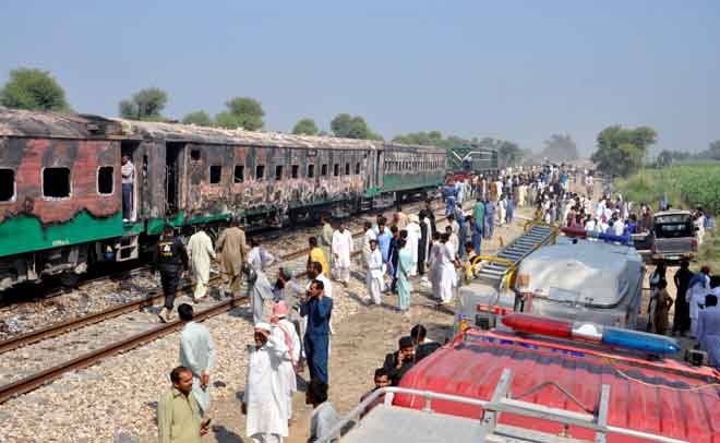  Orang ramai melihat gerabak yang hangus sehari selepas sebuah kereta api penumpang terbakar dan mengorbankan 74 nyawa di Rahim Yar Khan, di timur laut Pakistan semalam. — Gambar Arif Ali/AFP 