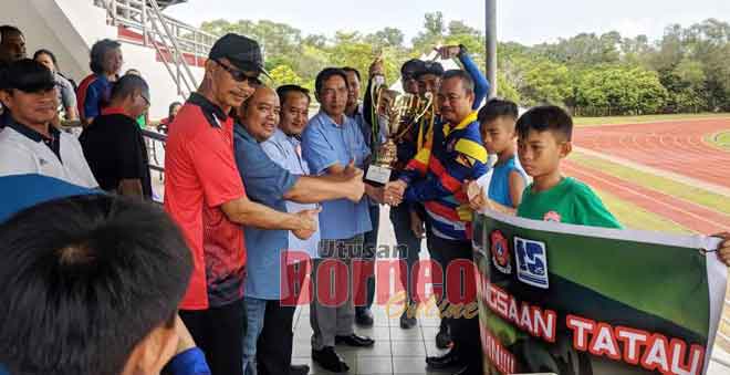  Kontinjen SK Tatau (kanan) menerima hadiah piala pusingan daripada Gilbert sambil disaksikan Samri (kiri) dan serta yang lain.