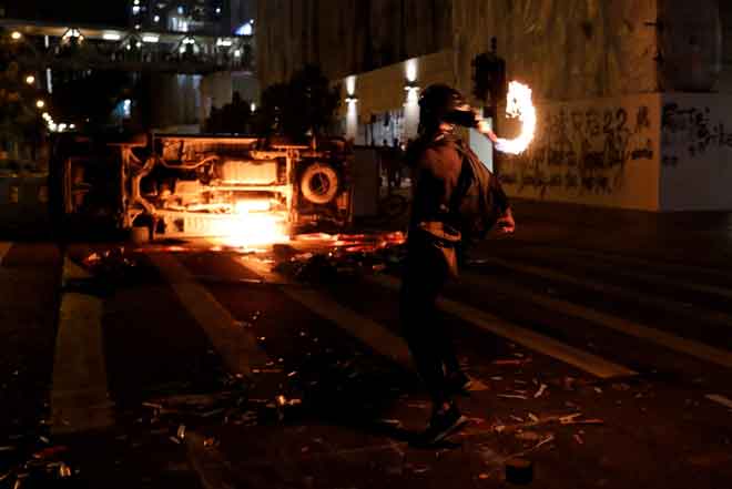  Penunjuk perasaan antikerajaan melontar bom botol ke arah kenderaan yang diterbalikkan semasa protes di daerah Tseung Kwan O, Hong Kong, China kelmarin. — Gambar Tyrone Siu/Reuters