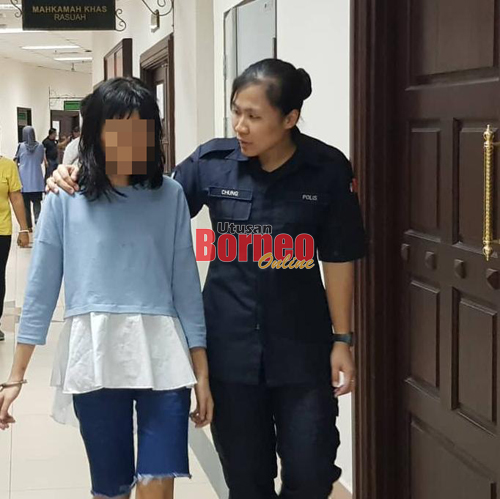 Suspek diiringi polis menuju ke bilik tahanan Mahkamah Kuching, hari ini.