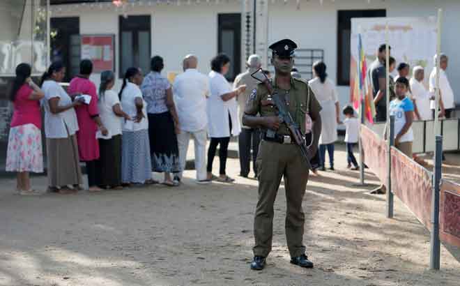  Anggota polis berkawal ketika orang ramai berbaris untuk membuang undi dalam pilihan raya presiden  di Colombo, Sri Lanka semalam. — Gambar Reuters 