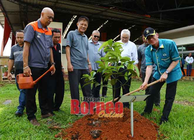  Junaidi (kanan) menanam pokok manggis, sambil disaksikan Abdul Jaafar (tiga kiri) dan yang lain. — Gambar Muhamad Rais Sanusi