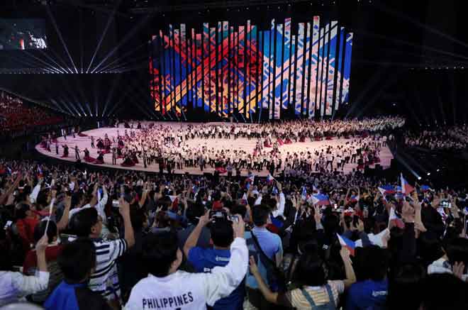  Orang ramai mengambil gambar menggunakan telefon bimbit masing-masing ketika delegasi tuan rumah berjalan ke atas pentas semasa upacara pembukaan penuh gilang gemilang di Philippine Arena di Bocaue, lewat kelmarin. — Gambar Reuters