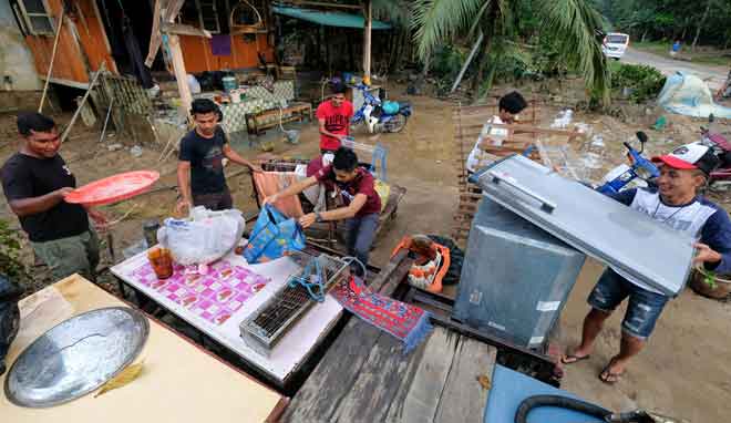  Raja Firdaus Raja Kamaruddin, 24, (kiri) dibantu rakan-rakannya mengemas kedai makanan milik keluarganya yang rosak selepas dilanda banjir ketika tinjauan di Kampung La, Jerteh semalam. — Gambar Bernama