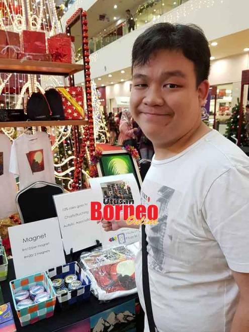 Alister menunjukkan salah satu daripada hasil seninya di Bazar Xmas, baru-baru ini.