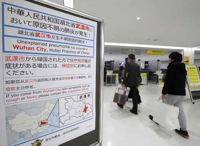  Penumpang berjalan melintasi papan tanda, yang memberi amaran mengenai penularan virus misteri di bandar Wuhan, China, di Lapangan Terbang Narita di Chiba, Jepun kelmarin. — Gambar AFP