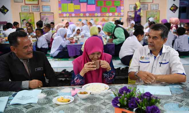  Dr Tajuddin (kanan) melihat guru Sekolah Kebangsaan (SK) Temin, Rifqah Norzari (tengah) mencuba terlebih dahulu makanan yang dibekalkan dalam Program Penambahbaikan Rancangan Makanan Tambahan 2020 ketika tinjauan semalam. — Gambar Bernama