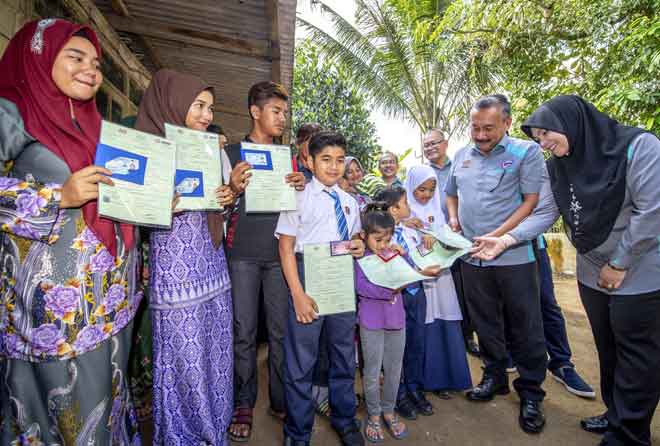  Ruslin (dua kanan) menyampaikan dokumen Sijil Kelahiran dan Kad Pengenalan kepada adik Che Danish Haikal, 7, salah seorang daripada lapan beradik yang menerima dokumen Sijil Kelahiran dan Kad Pengenalan di rumah mereka di Kampung Demit Sungai Kubang Kerian, Kota Bharu semalam. Turut hadir, Pengarah JPN Kelantan Asrehan Ab Razak (kanan). Lapan daripada 15 beradik itu menerima dokumen Sijil Kelahiran dan Kad Pengenalan mereka semalam. — Gambar Bernama