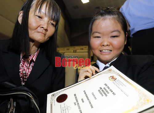 Jane ditemani ibunya, Ngu Leh Ching menunjukkan sijil keputusan cemerlangnya.