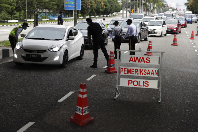 Anggota Polis Trafik dari Balai Polis Trafik Kuala Lumpur memeriksa deretan kenderaan yang bergerak keluar dari ibu kota susulan Perintah Kawalan Pergerakan yang dilaksanakan di bawah Akta Pencegahan dan Pengawalan Penyakit Berjangkit 1988 dan Akta Polis 1967 mulai 18 Mac hingga 31 Mac ini dalam sekatan jalan raya di Jalan Loke Yew pada Selasa. - Gambar Bernama 